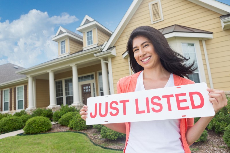 woman holding just listed sign